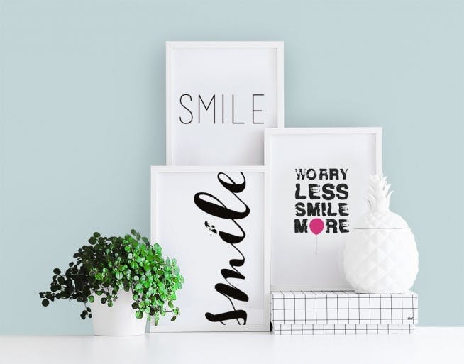 Små plakater i hvide rammer med teksten Smile til billedvæg