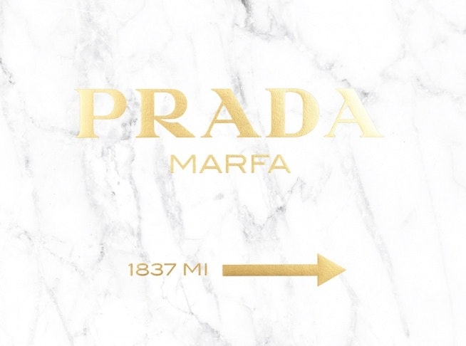 Print with a gold text Prada Marfa against a marble background